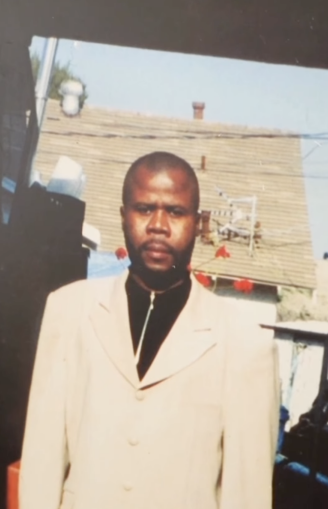 Older photograph of a younger Festus standing outdoors in a light-colored suit.