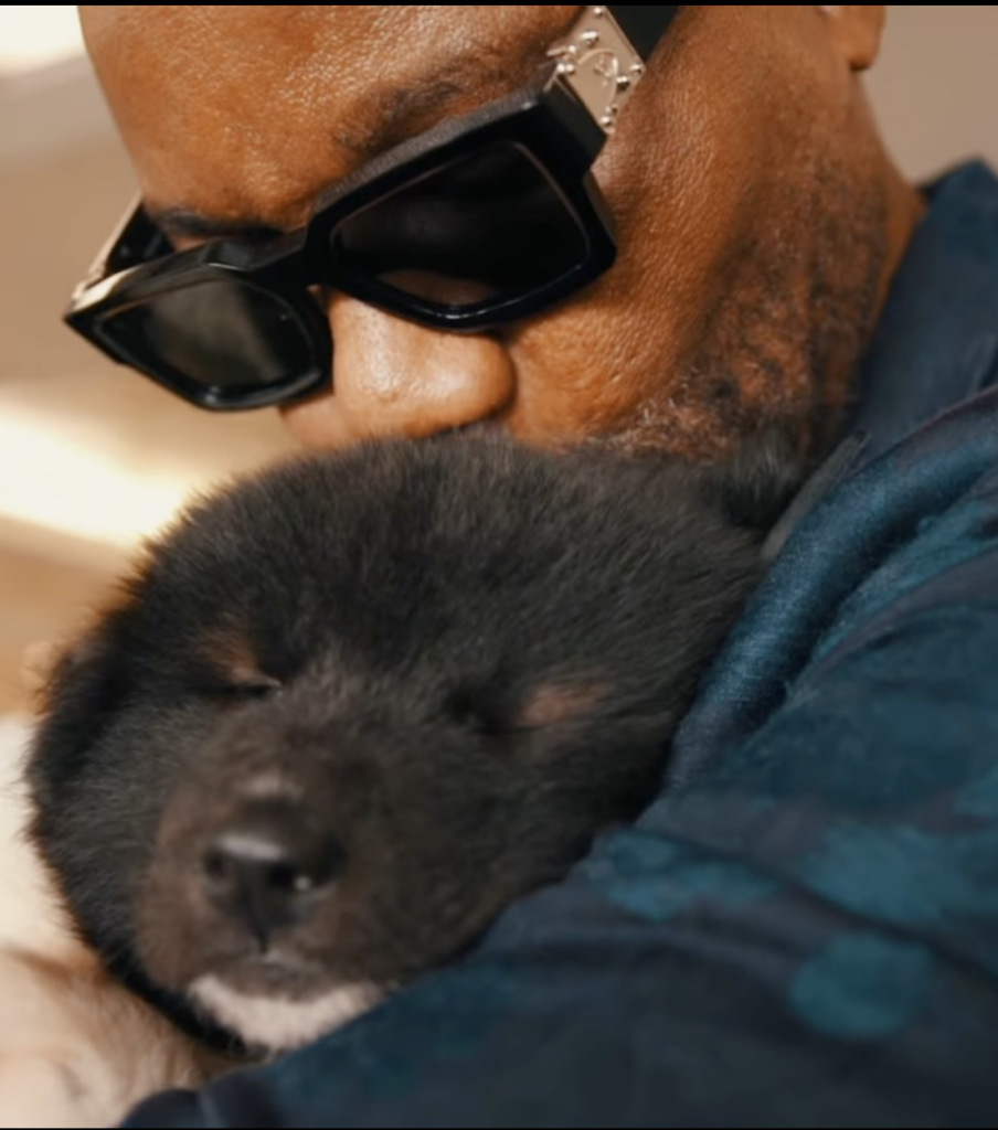 Dr. Sanusi Umar wearing dark glasses while holding a small black puppy.