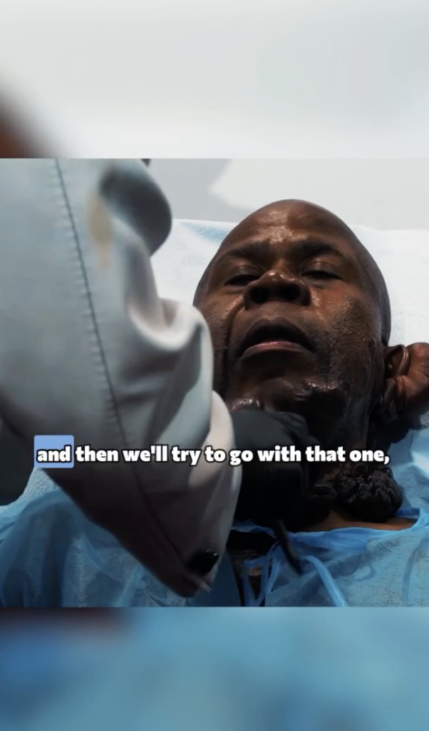 Festus lying on a treatment table as a gloved clinician examines raised lesions beneath his chin and neck.