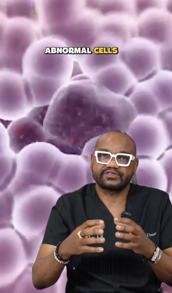 Dr. Sanusi Umar speaking in front of a purple microscopic-style background with the words “abnormal cells.”