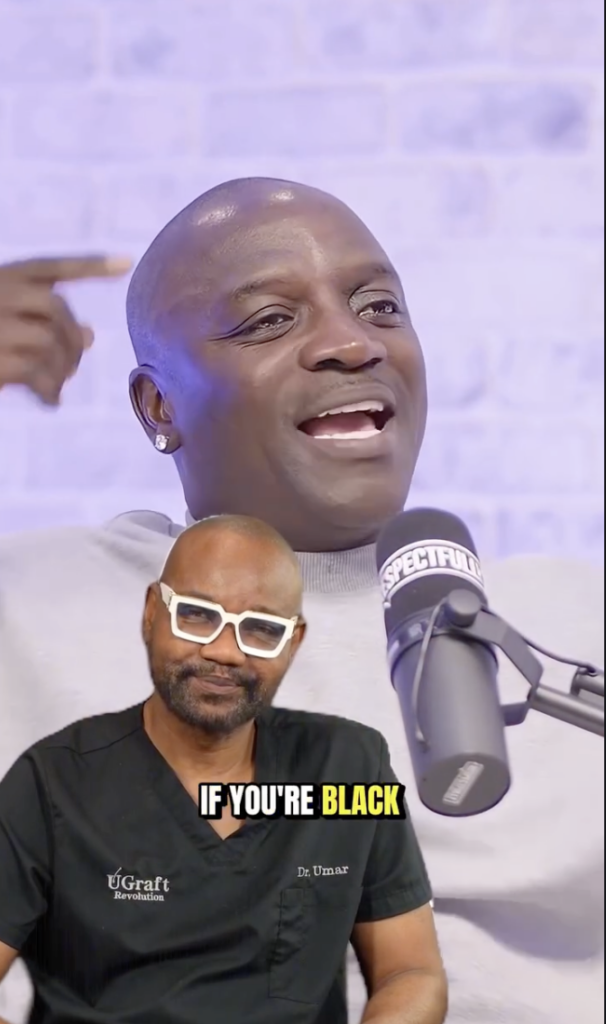 Man speaking into a studio microphone with Dr. Sanusi Umar seated in the foreground wearing black scrubs and white-framed glasses.