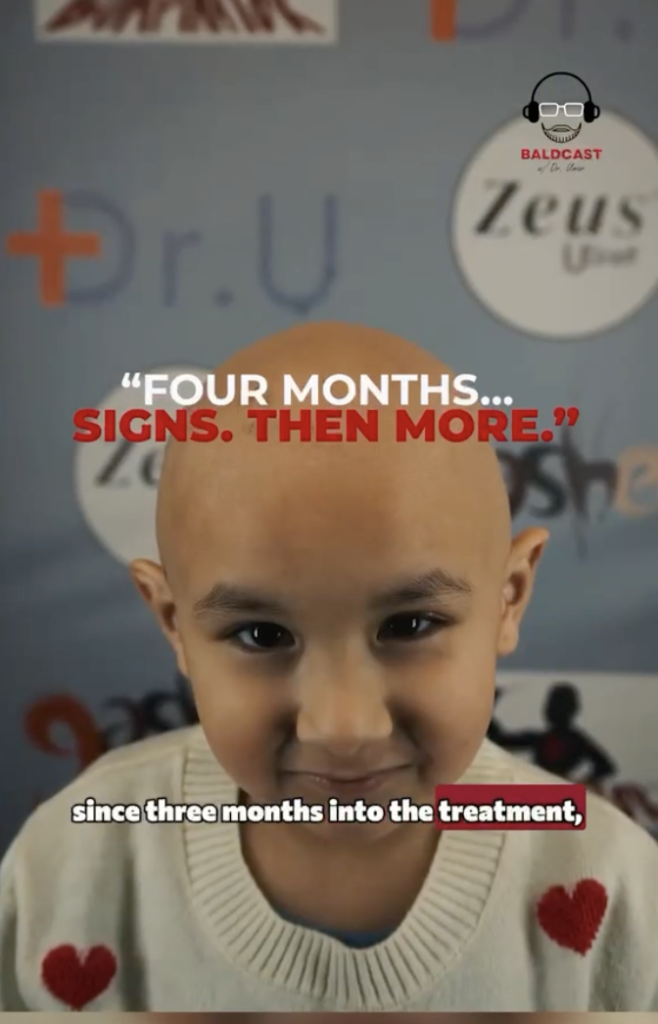 Mia with a shaved scalp wearing a cream sweater with red hearts, with on-screen text about signs appearing around four months.