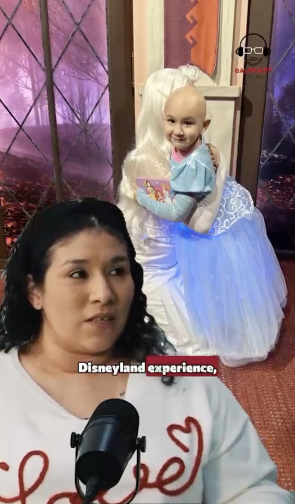 A child with a bald head hugging a costumed princess character, with Mia’s mother shown speaking in the foreground.